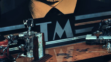 Close-up on the letters 'TM' under the portrait of Greg in the living room.