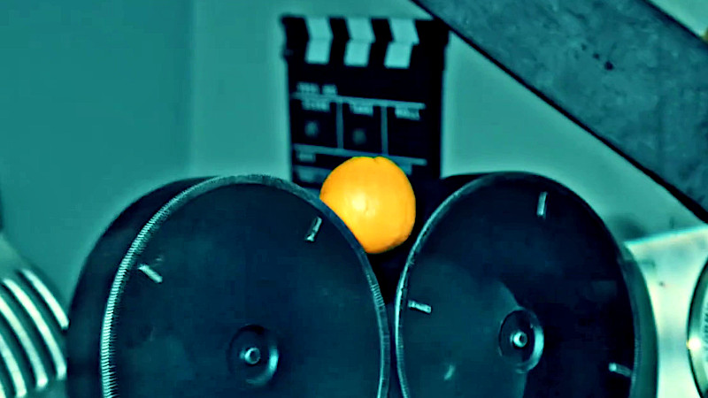 An orange resting between the two film canisters of a film camera. An orange resting between the two film canisters of a film camera.