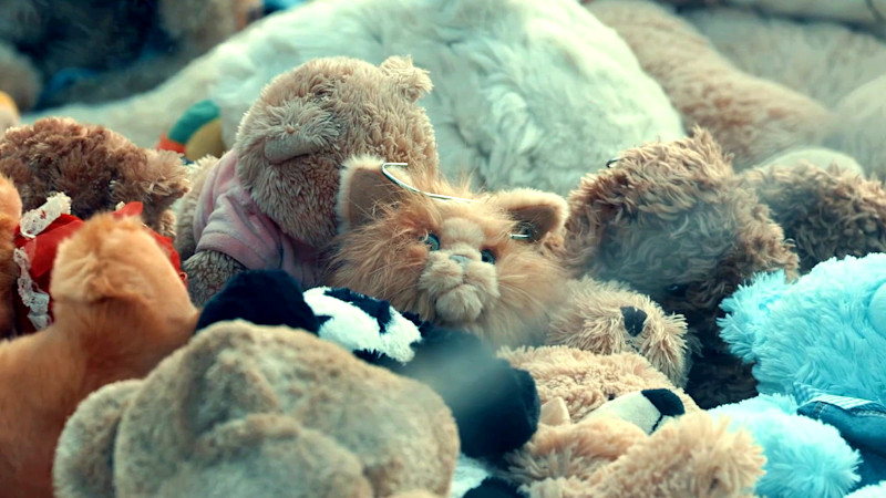 Patatas the cat plushie peeking out from a sea of other plush toys. Patatas the cat plushie peeking out from a sea of other plush toys.