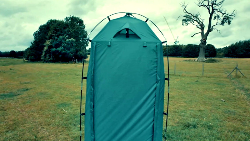 A blue green standing tent on a field. A blue green standing tent on a field.