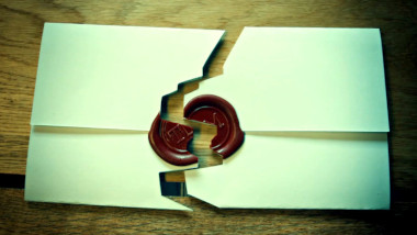 A sealed task that has been cut jaggedly down the middle rests on a wooden table.
