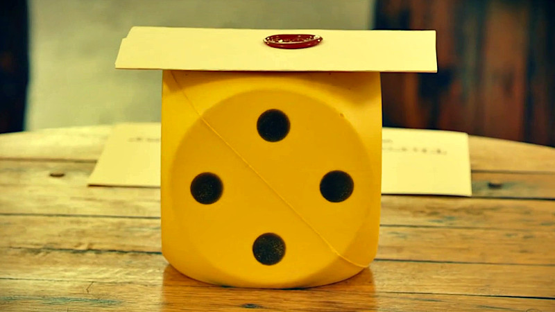 The task brief on top of a giant yellow die, which is on top of a barrel. The task brief on top of a giant yellow die, which is on top of a barrel.