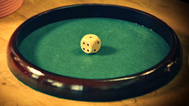 A six-sided die on a green felt rolling tray.